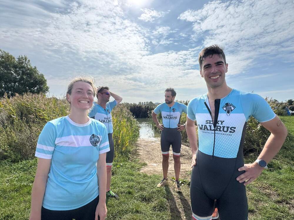 Club members in kit beside the water in the sun