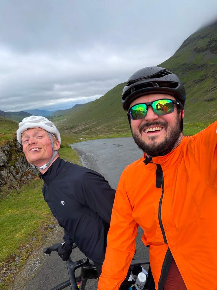 Two riders on a hill, one wearing orange