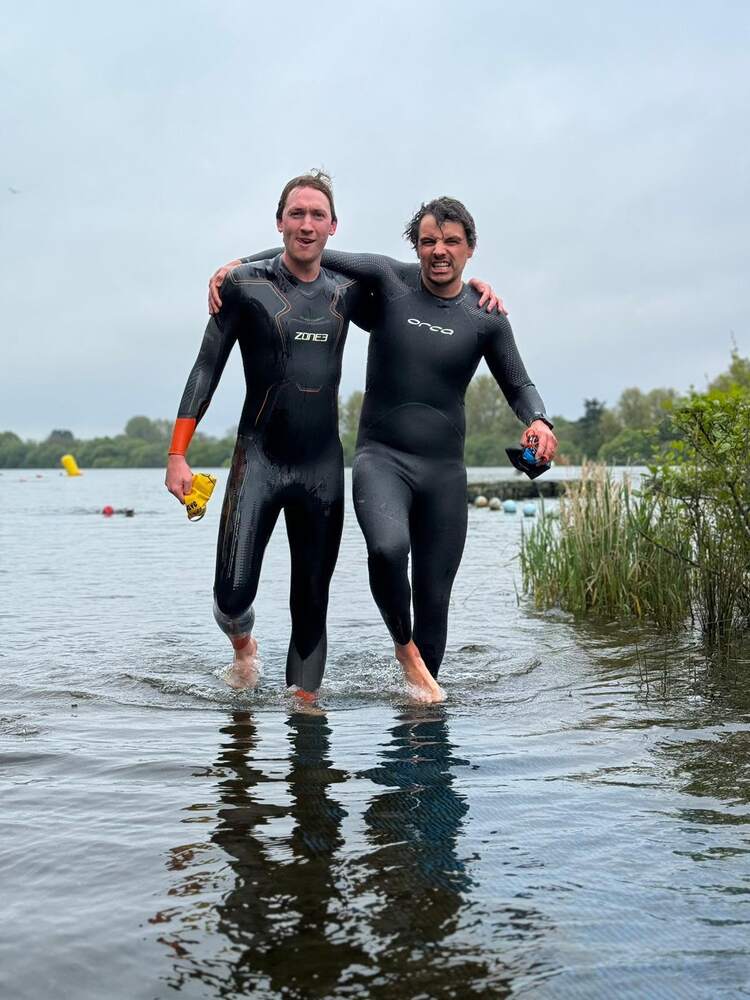 Two members in wetsuits walking out of the water