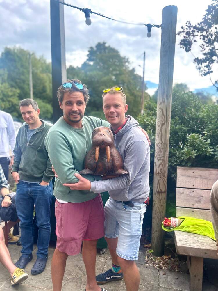 Two club members holding a carved wooden walrus at a club gathering